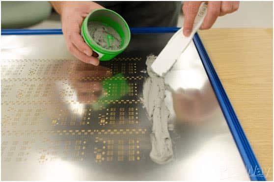 A stencil, with solder paste being applied using a squeegee